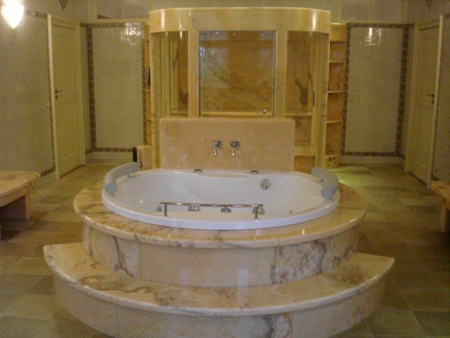 Bagno rivestito in marmo con vasca centrale e boiserie in lastra