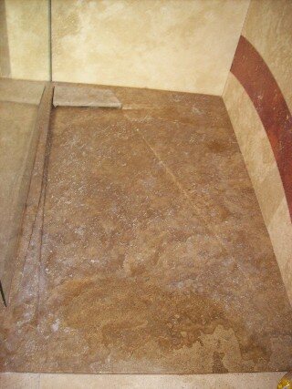 Piatto doccia in travertino posato a filo pavimento con canalina di scolo