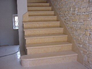 Scala a rampa in pietra chiara accostata a una parete in pietra a spacco